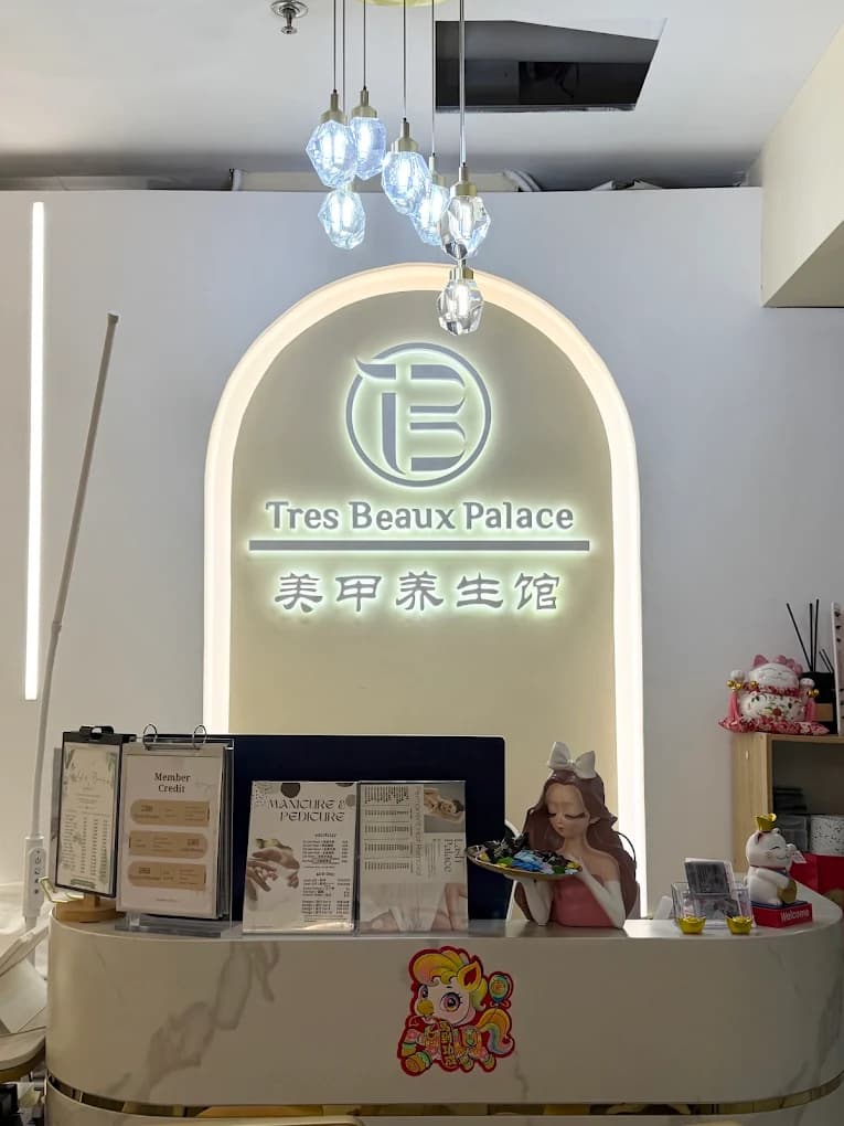 The reception counter at Tres Beaux Palace, beneath the illuminated logo sign